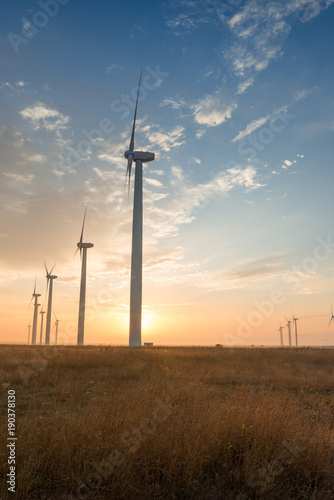 Wind turbines against red, blue and orange sunrise