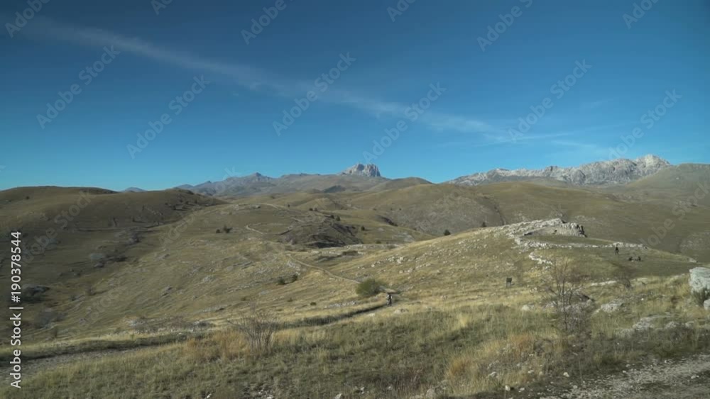 Hills and valleys with desert paths under clear blue sky.