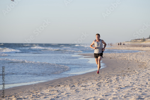 athletic fit and strong runner man training on Summer sunset beach in sea shore running and fitness workout in sport and healthy lifestyle © Wordley Calvo Stock