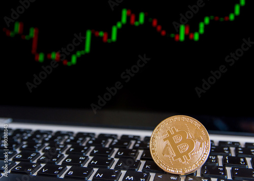 Golden bitcoin coins on keyboard laptop with trading chart background