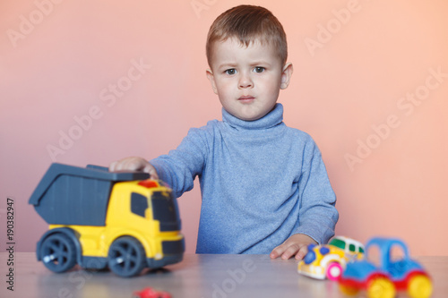 A cute little boy playing with model car collection. Toy mess in child room. Educational games for kids.