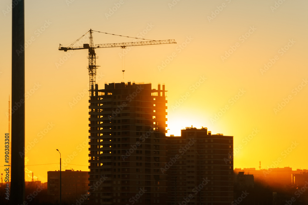 Construction crane and skyscraper at sunset