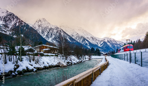 Beautiful touristic landscape of snow  mountain  river  and pine tress in a small village in Chamonix Mont Blanc in France.  Cloudy sky in winter.  The water is very clean  coming from the mountain. 