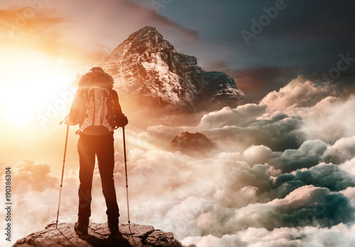 Bergsteigerin steht auf Gipfel und genießt Sonnenaufgang