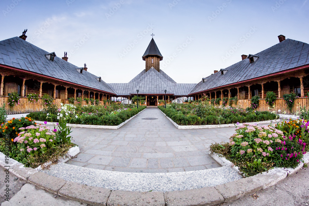 Wide view of the inner yard of St. Ana wood church full of flowers, Orsova, Romania