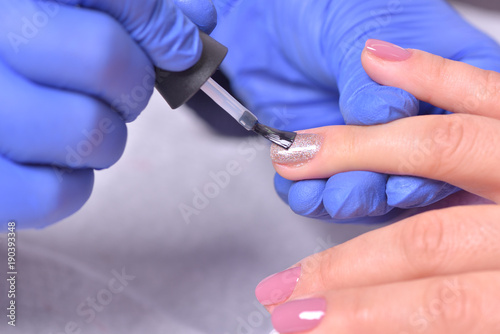 Nail Care And Manicure. Closeup Of Beautiful Female Hands Applying Transparent Nail Polish On Healthy Natural Woman s Nails In Beauty Salon. Manicurist Hand Painting Client s Nails. High Resolution