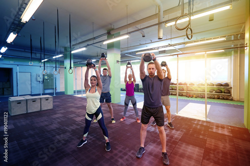 group of people with kettlebells exercising in gym