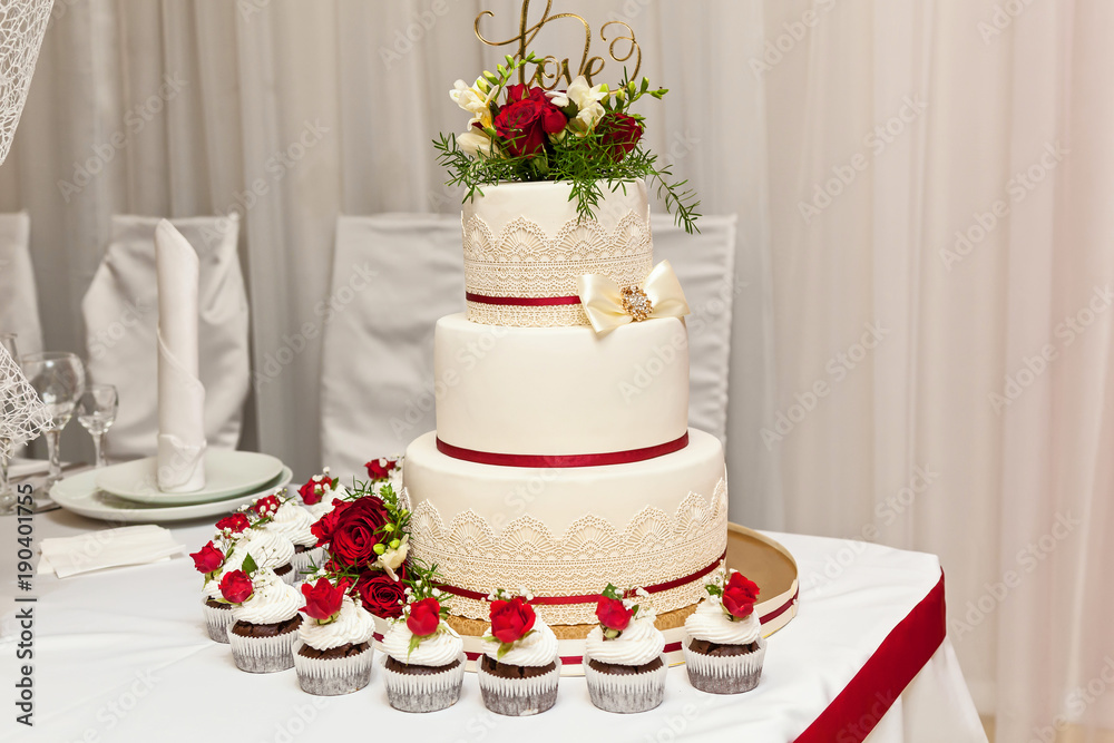 Image of a beautiful wedding cake at wedding reception. wedding cake with red roses Image of a beautiful wedding cake at wedding reception. wedding cake with red roses