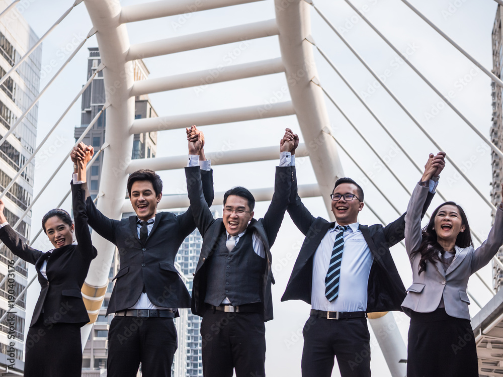 Successful Asian business team celebrating their triumph with arms up. Teamwork and success concept Successful Asian business team celebrating their triumph with arms up. Teamwork and success concept