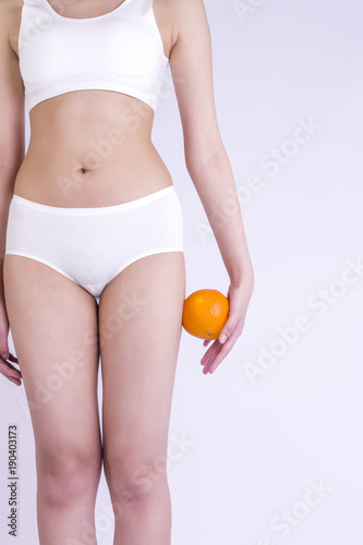 Hip, legs, abdomen and orange in hand. Cellulite, liposuction ,woman weight loss control concept.