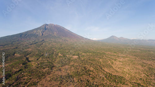 Aerial view of Volcano Mount Agung with smoke billowing out at sunrise, Bali, Indonesia. Conical volcano of Gunung Agung. Rural mountain landscape.