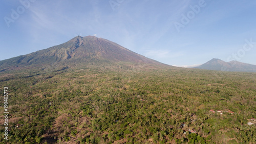 Aerial view of Volcano Mount Agung with smoke billowing out at sunrise, Bali, Indonesia. Conical volcano of Gunung Agung. Rural mountain landscape.