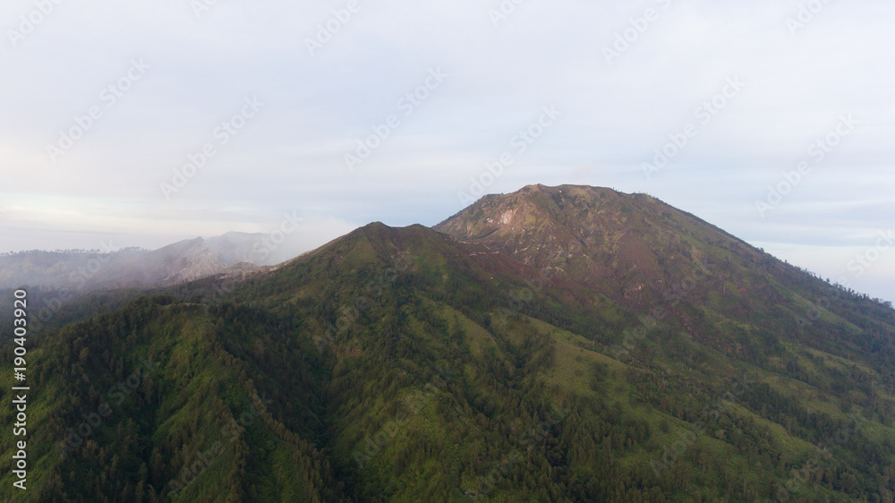 Beautiful sunset in the mountains on Jawa island, Indonesia. Aerial view of mountains landscape under sky with clouds, rainforest.