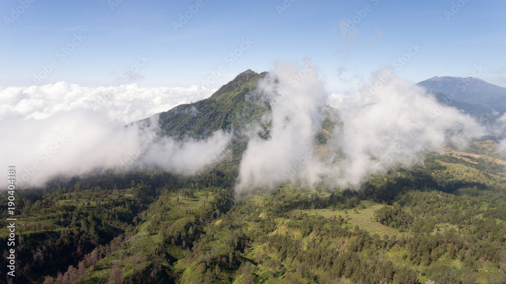 Tops of the mountains covered with forest in running clouds and fog at sunrise. Landscape slopes of the mountains with the forest in the morning fog and clouds.Slopes of the mountains are covered with