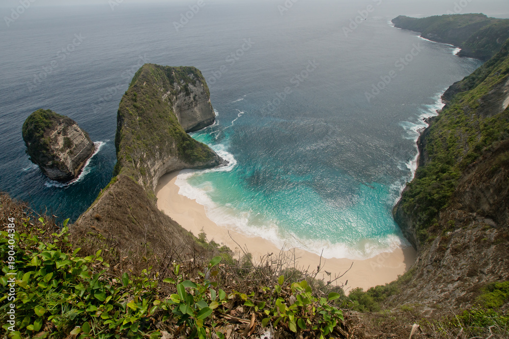 Beach with turquoise water among the rocks. Tropical beach among rocky cliffs. Karang Dawa, Manta Bay or Kelingking Beach on Nusa Penida Island, Bali, Indonesia.Travel concept. - obrazy, fototapety, plakaty 