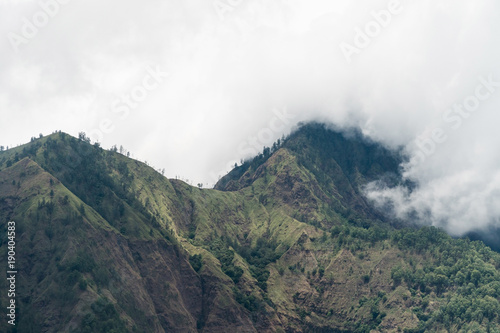 Tops of the mountains covered with forest in clouds and fog. Slopes of the mountains are covered with rainforest Bali  Indonesia. Mountain landscape  sky and clouds. Travel concept