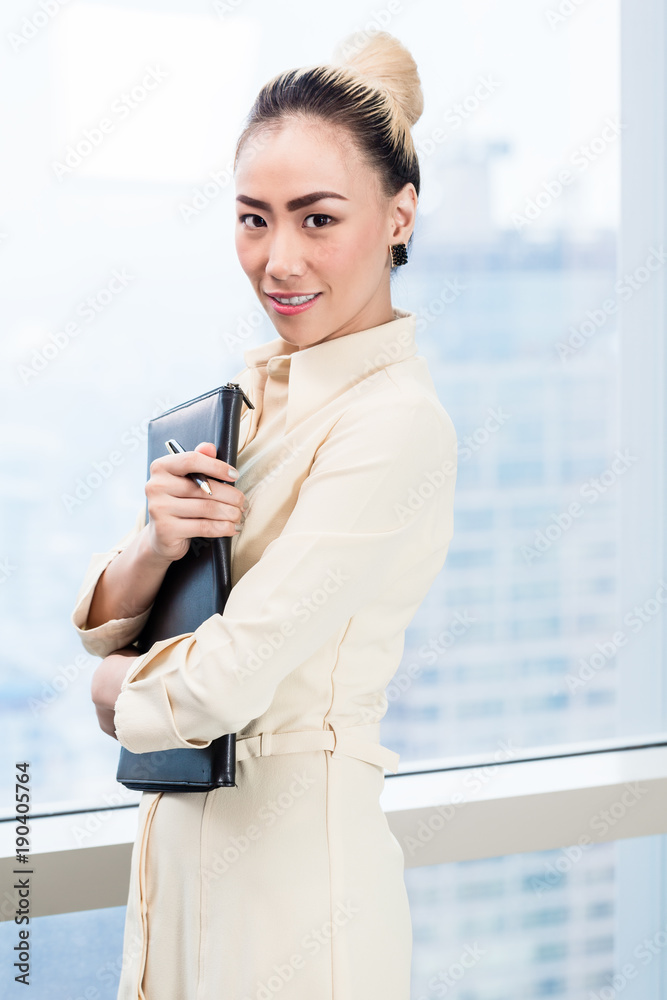 Asian businesswoman in front of skyscraper window in office Asian businesswoman in front of skyscraper window in office