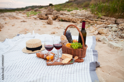 Picnic on the beach at sunset in the white plaid, food and drink conception