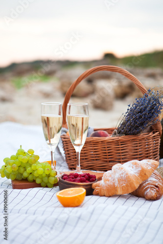 Two glasses of champagne. Picnic on the beach at sunset in the white plaid, food and drink conception
