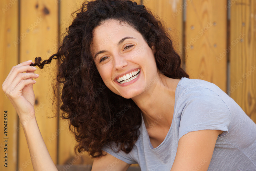 Close up happy young woman smiling with hand in hair Close up happy young woman smiling with hand in hair