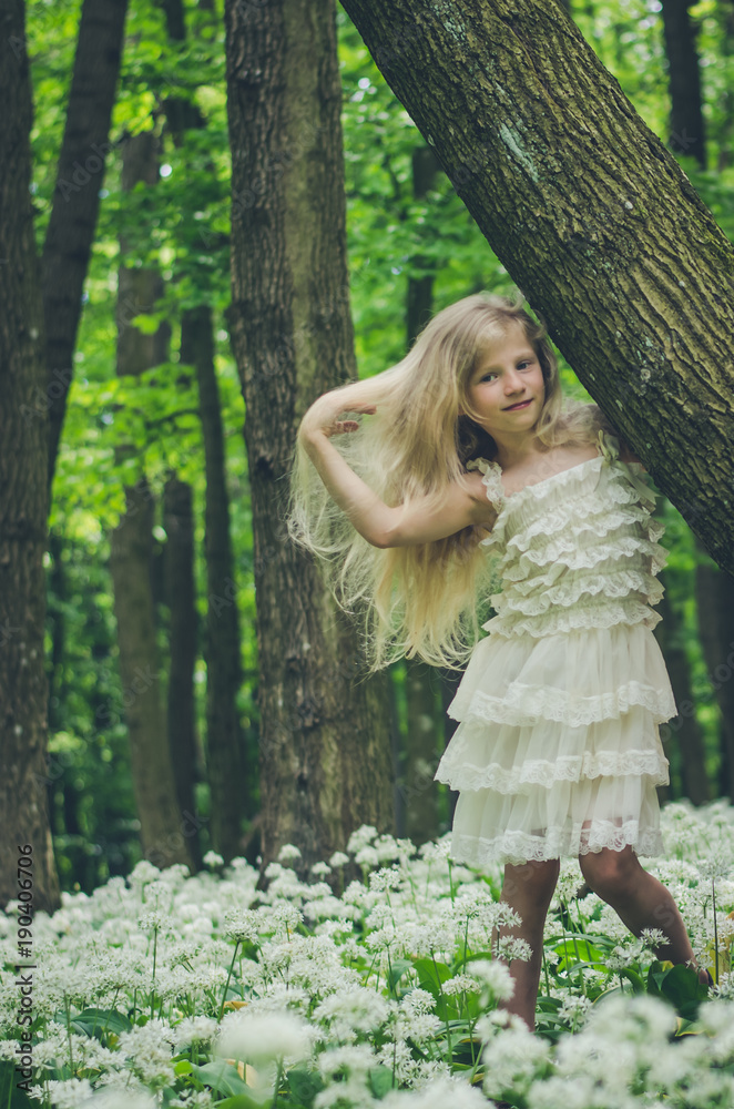 Naklejka premium lovely girl in white dress posing in spring forest