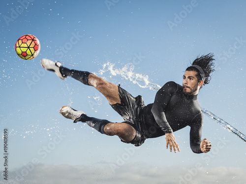 Water spraying on man kicking soccer ball photo