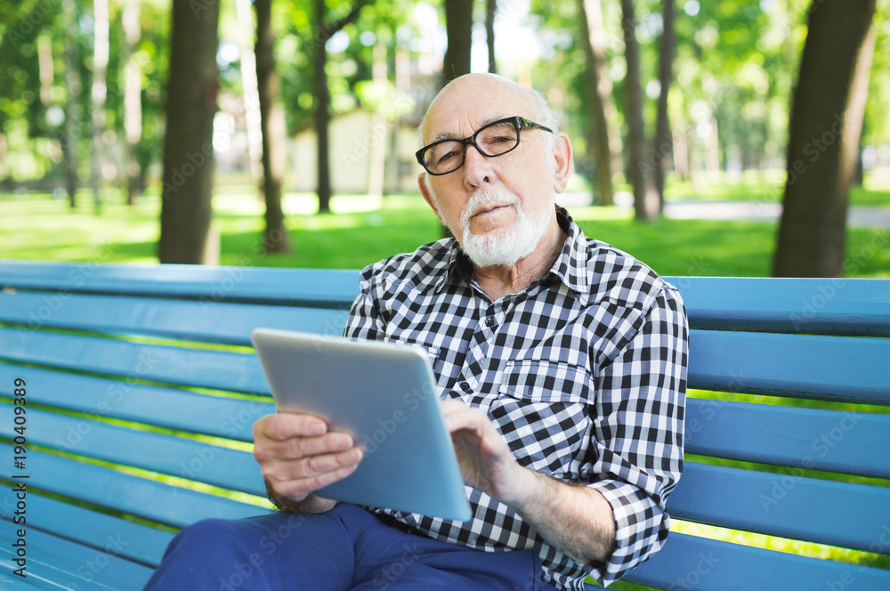 Senior man in casual with digital tablet outdoors Senior man in casual with digital tablet outdoors