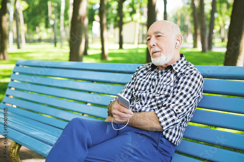 Happy senior man in earphones outdoors