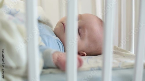 Close up of a little baby boy sleeping, baby lying in baby cot photo