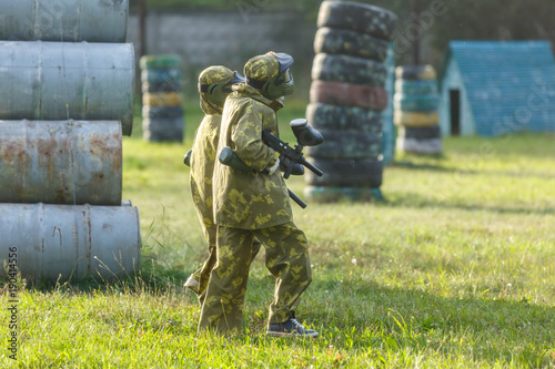 kids play paintball on special field with barrels  tires in the summer