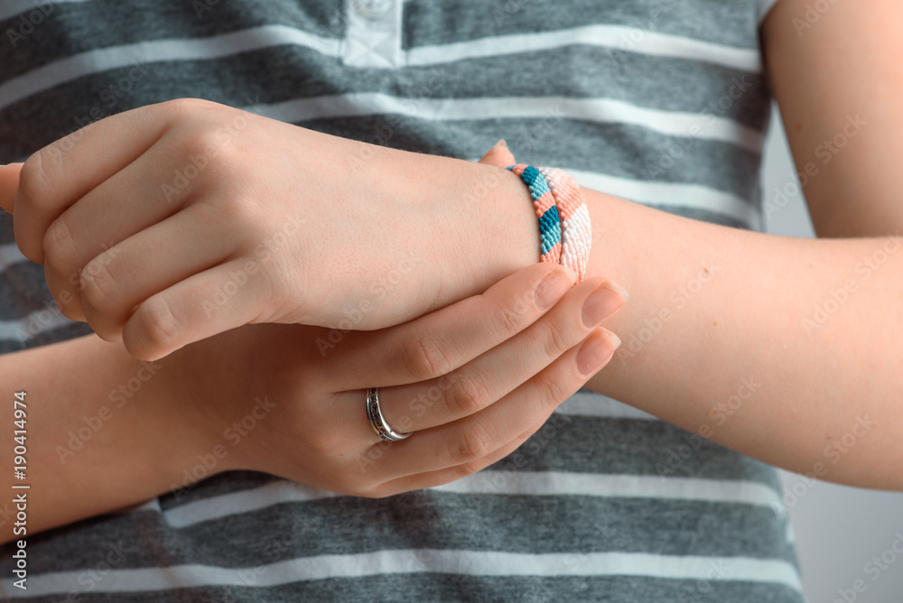 Horizontal toned shot of a female hand wearing braided bracelets