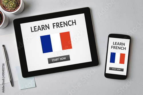 Learn French concept on tablet and smartphone screen over gray table. All screen content is designed by me. Flat lay