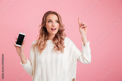 Woman showing display of mobile phone while pointing.