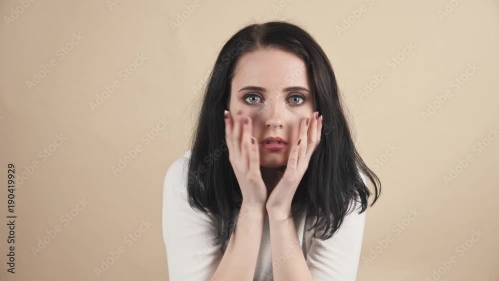 a young beautiful cute brunette on a beige orange background showing fear, disgust, horror, sadness, trembling, nervousness, scarry emotions a young beautiful cute brunette on a beige orange background showing fear, disgust, horror, sadness, trembling, nervousness, scarry emotions