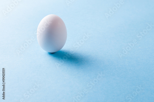 White egg with shadow on blue background. A good hearty breakfast of boiled eggs. Copy space for text