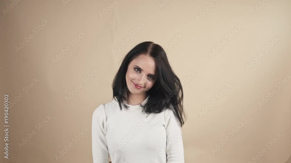 a young beautiful cute brunette on a beige orange background showing pride, joy, excellence, impeccability, happiness, cool, strong, biceps emotions a young beautiful cute brunette on a beige orange background showing pride, joy, excellence, impeccability, happiness, cool, strong, biceps emotions