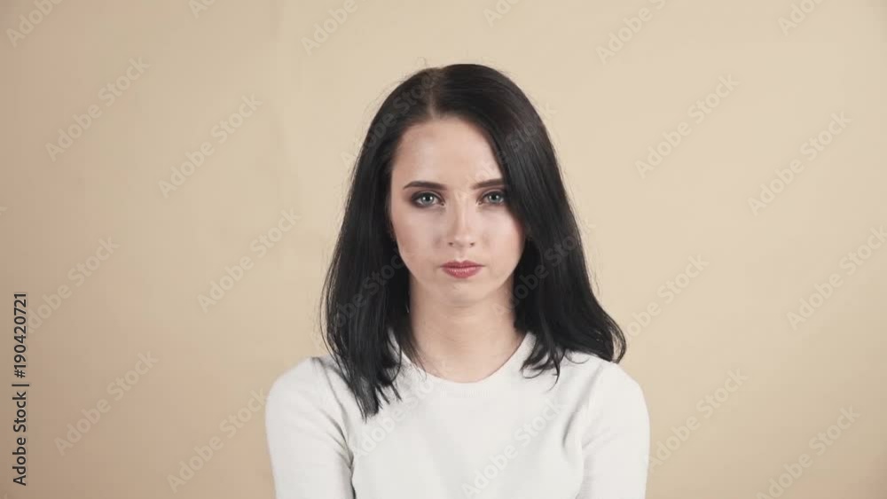 a young beautiful cute brunette on a beige orange background showing rage, anger, madness emotions a young beautiful cute brunette on a beige orange background showing rage, anger, madness emotions