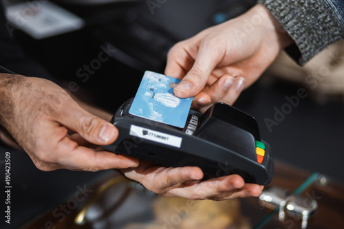 Customer is paying with contactless credit card in shop.
