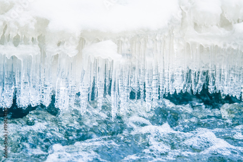A beautiful frozen icicles at the bank of river in Latvia. Beautiful winter scenery.