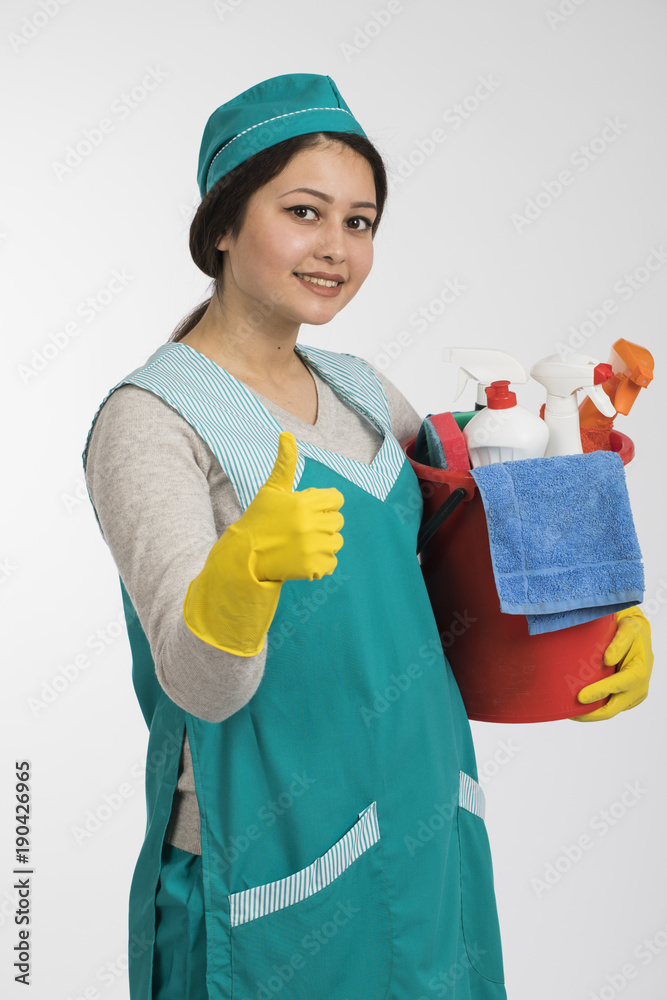 Young woman holding cleaning tools and products in bucket Young woman holding cleaning tools and products in bucket