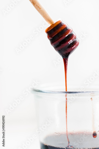 pomegranate molasses dripping into jar