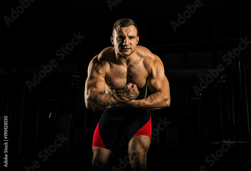 The weightlifter is posing in front of the camera, monstrously straining his arms as he screams from the tension. photo