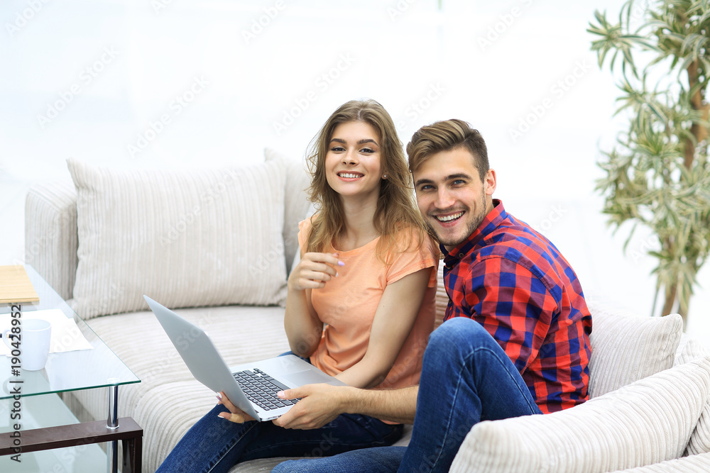 pair students with a laptop sitting on sofa pair students with a laptop sitting on sofa