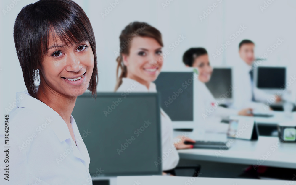 Business woman with a computer at the office with a group behind.