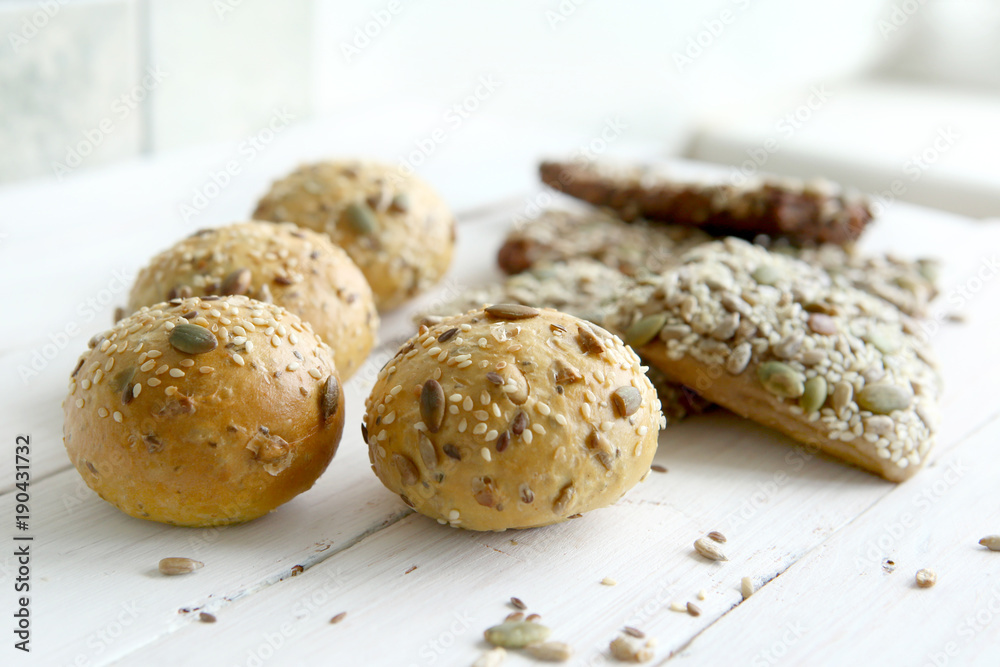 Bread buns with various seeds on white wooden table. Bread roll and breadsticks with sesame, pumpkin, sunflower, flax seeds, Bread buns with various seeds on white wooden table. Bread roll and breadsticks with sesame, pumpkin, sunflower, flax seeds,