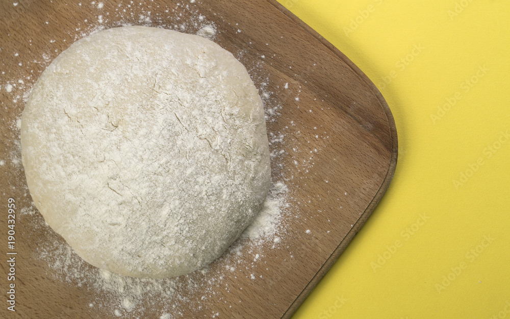 Loaf dough on wooden board on yellow background Loaf dough on wooden board on yellow background