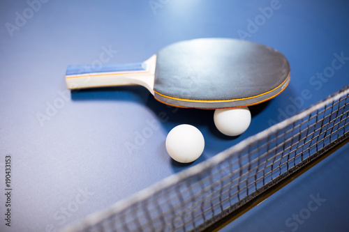 Ping pong racket / bat with white ball on a professional table