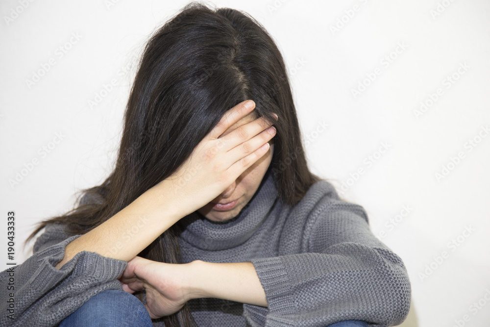 Closeup portrait of a stressed woman in a deep pain. Her face is pressed against her hands. Alone and lonely young girl feeling depressed. Closeup portrait of a stressed woman in a deep pain. Her face is pressed against her hands. Alone and lonely young girl feeling depressed.