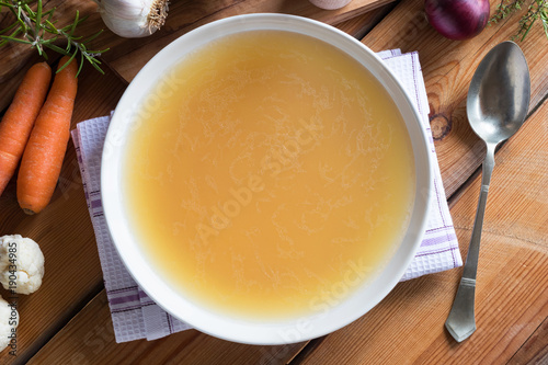 Bone broth made from chicken on a wooden table, top view photo