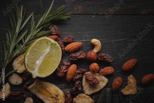 Mix of nuts, dried fruits and herbs on a black rustic background. © Max